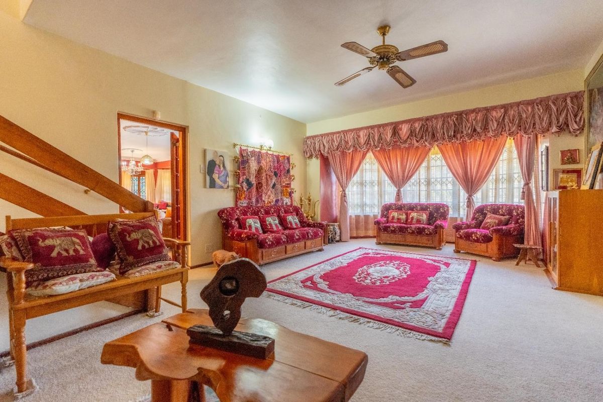Spacious living room featuring a ceiling fan, carpeted flooring, and a staircase leading to the upper level.