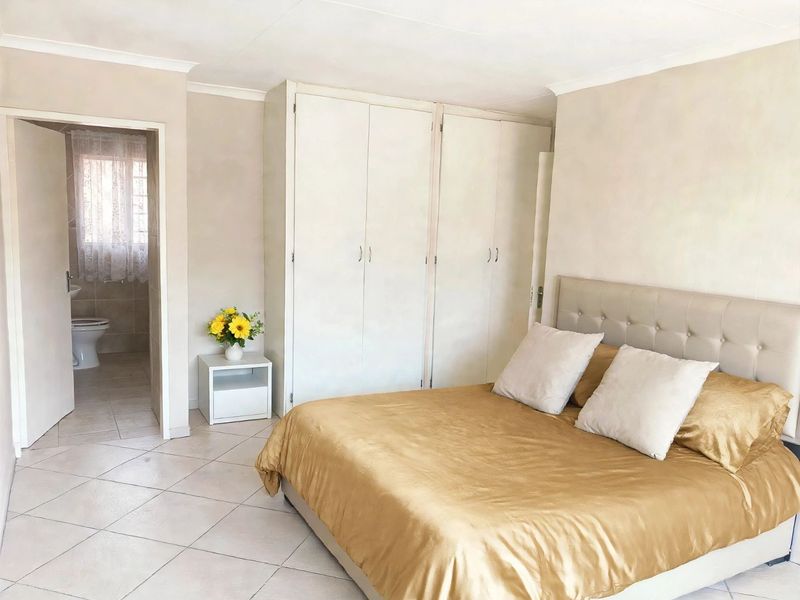 A bedroom featuring built-in cupboards, tiled flooring, and direct access to an en-suite bathroom.
