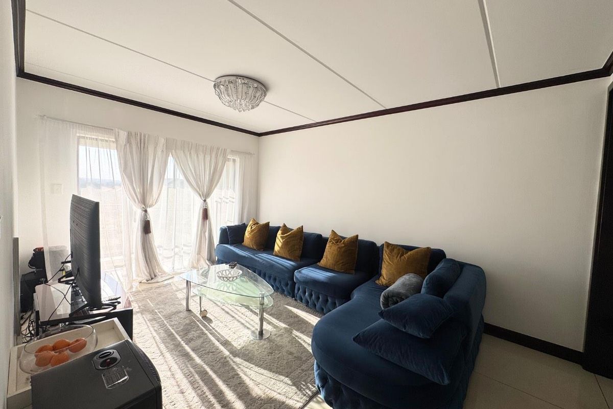 A bright living room featuring tiled flooring, a central ceiling light fixture, and a sliding glass door providing access to the exterior.