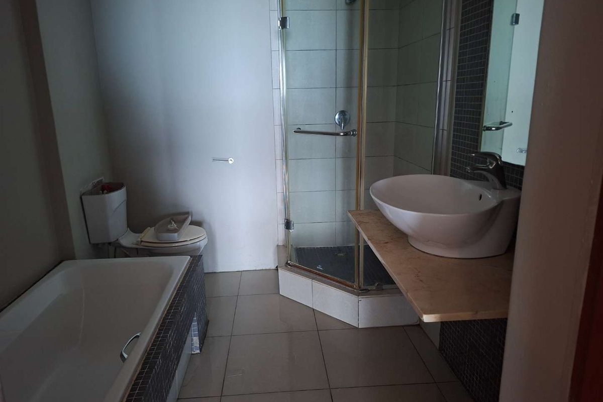 A functional bathroom featuring a separate shower enclosure, a bathtub with tiled surround, and a vessel sink mounted on a stone vanity shelf.
