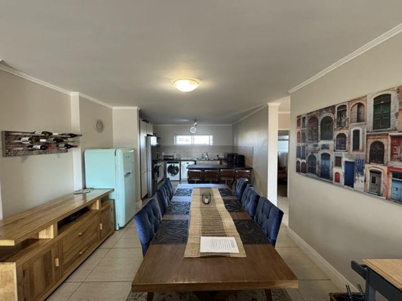 Open-plan living and dining area featuring tiled flooring and a functional kitchen space with built-in cabinetry and appliances.