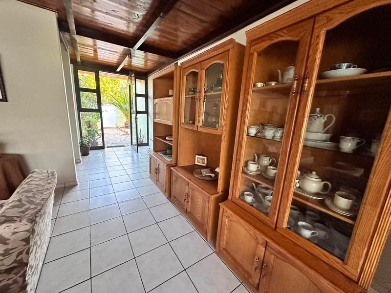 Living area featuring a warm timber ceiling, tiled flooring, and direct access to the outdoor patio through a glass panelled door.