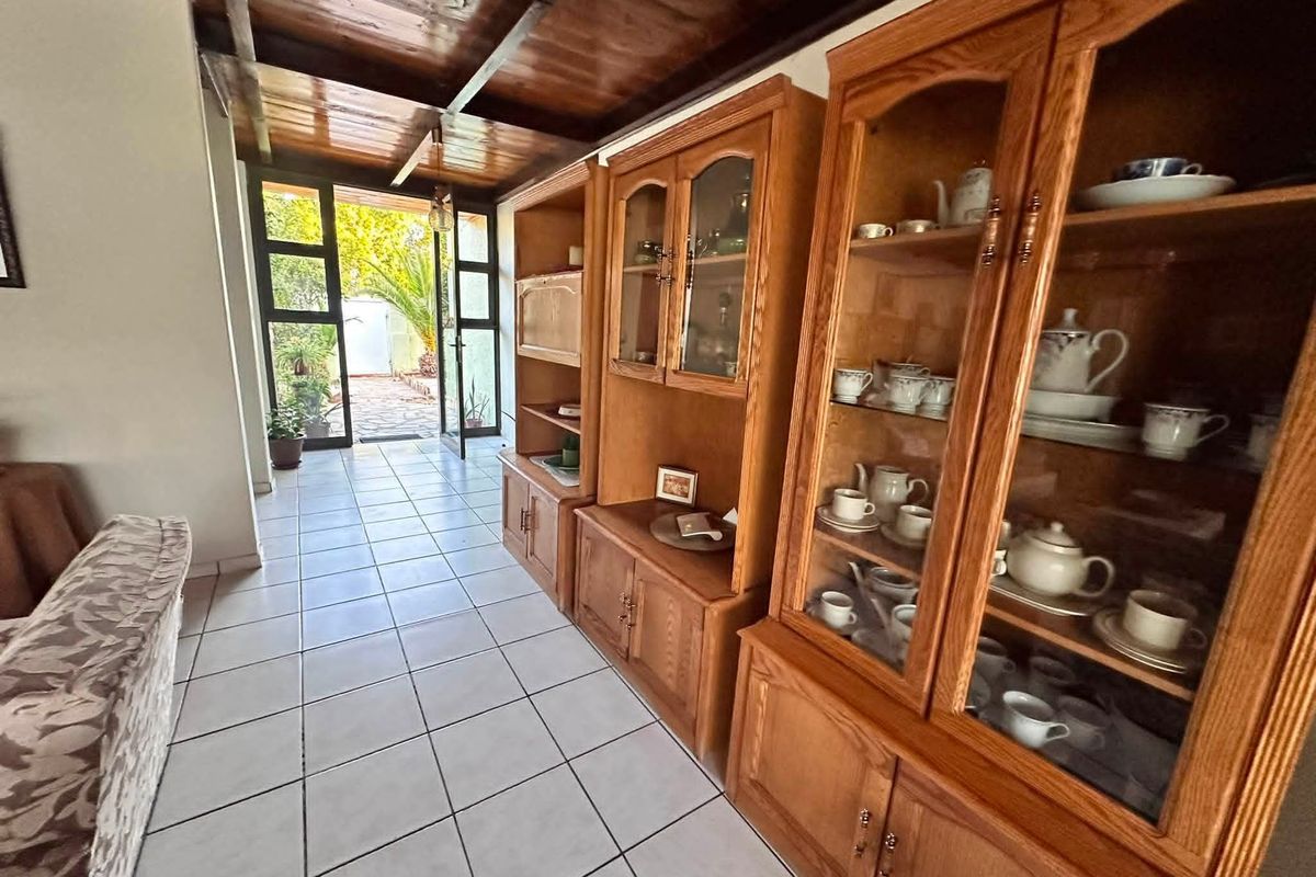 Living area featuring a warm timber ceiling, tiled flooring, and direct access to the outdoor patio through a glass panelled door.