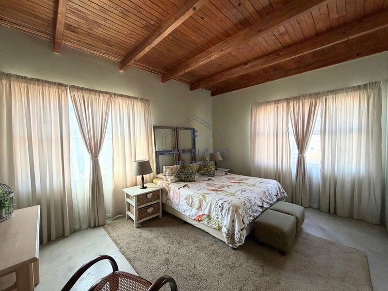 Spacious bedroom featuring a high exposed timber beam ceiling and polished concrete flooring, offering a rustic and airy atmosphere.