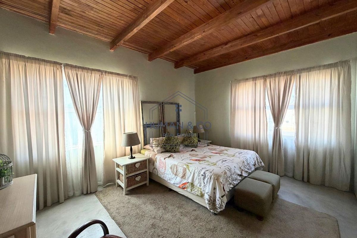 Spacious bedroom featuring a high exposed timber beam ceiling and polished concrete flooring, offering a rustic and airy atmosphere.