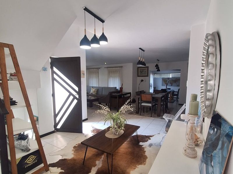 An open-plan living and dining area featuring tiled flooring, modern pendant lighting, and a contemporary front entrance door.