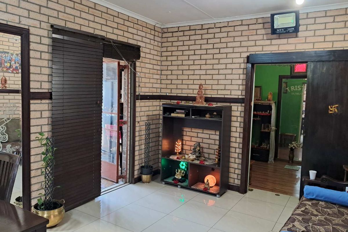 A living room featuring exposed brick walls, tiled flooring, and a doorway leading to an adjacent room.