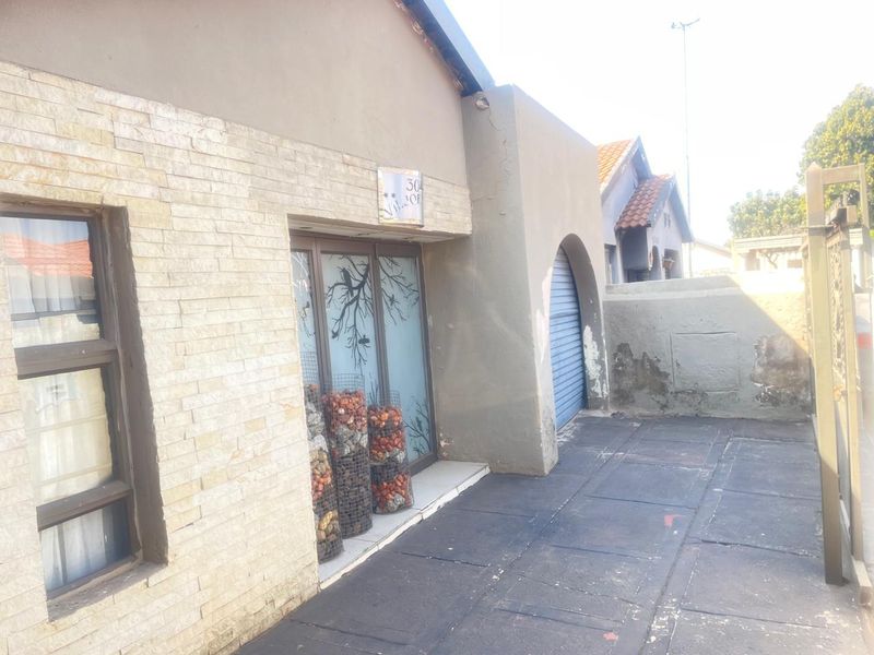 Front exterior view of the property featuring stone cladding, a roller shutter door, and a paved driveway area with visible wear on the boundary wall.