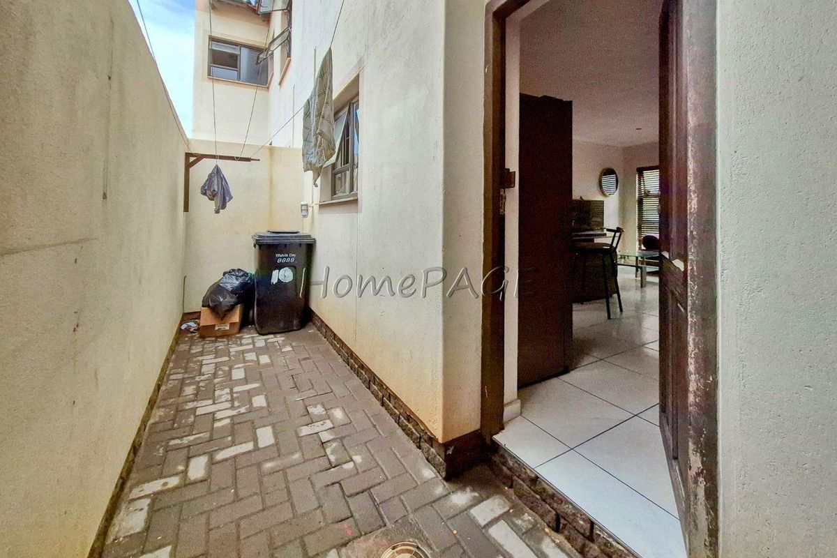 A narrow exterior side courtyard with paved flooring, providing access to the interior living area through a single door.