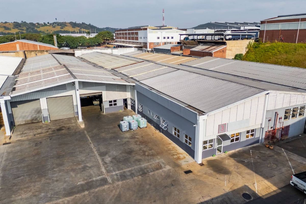 Aerial view of an industrial warehouse facility featuring corrugated metal roofing, roller shutter doors, and a large concrete yard area.