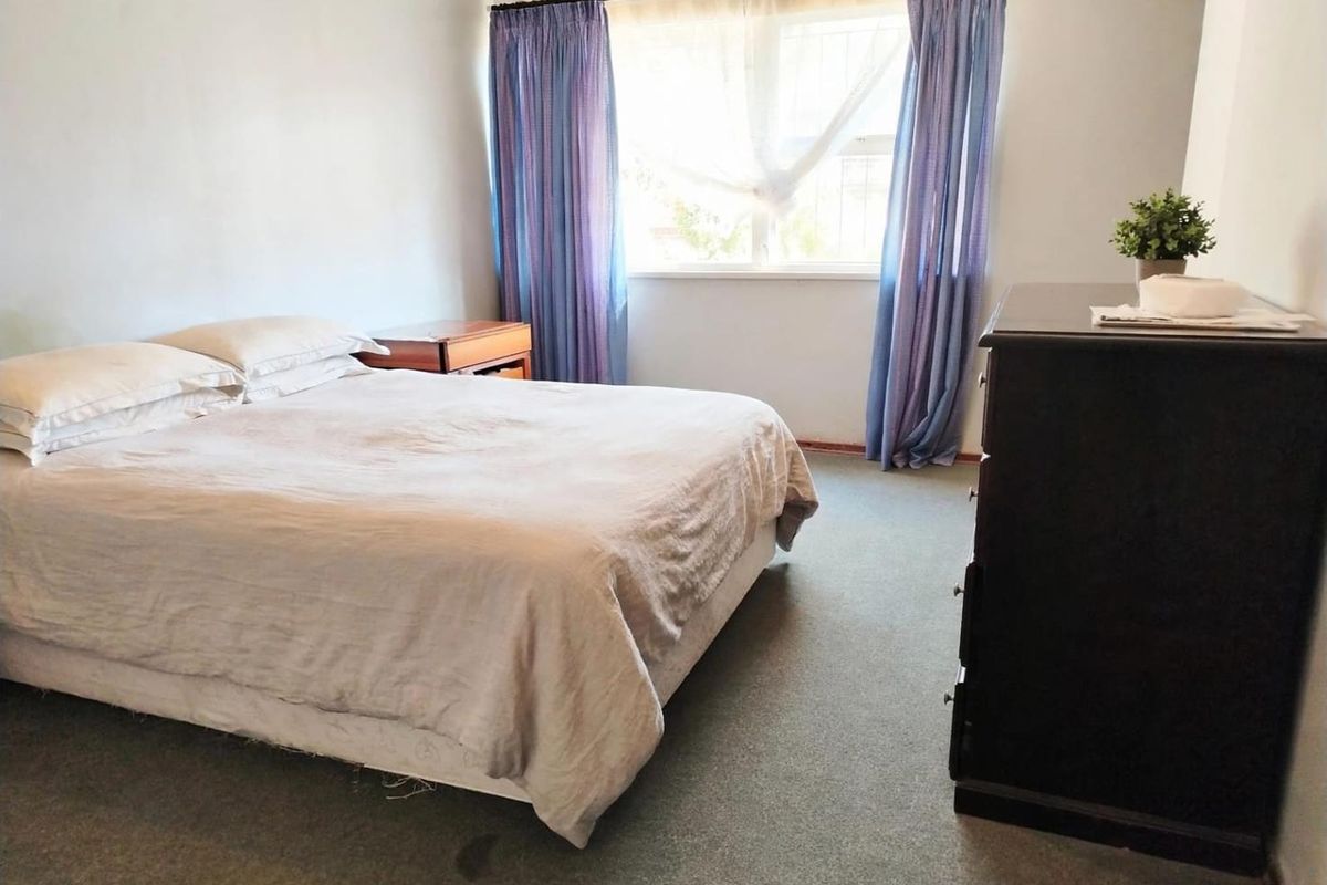 A standard bedroom featuring carpeted flooring and a window with curtain fixtures.
