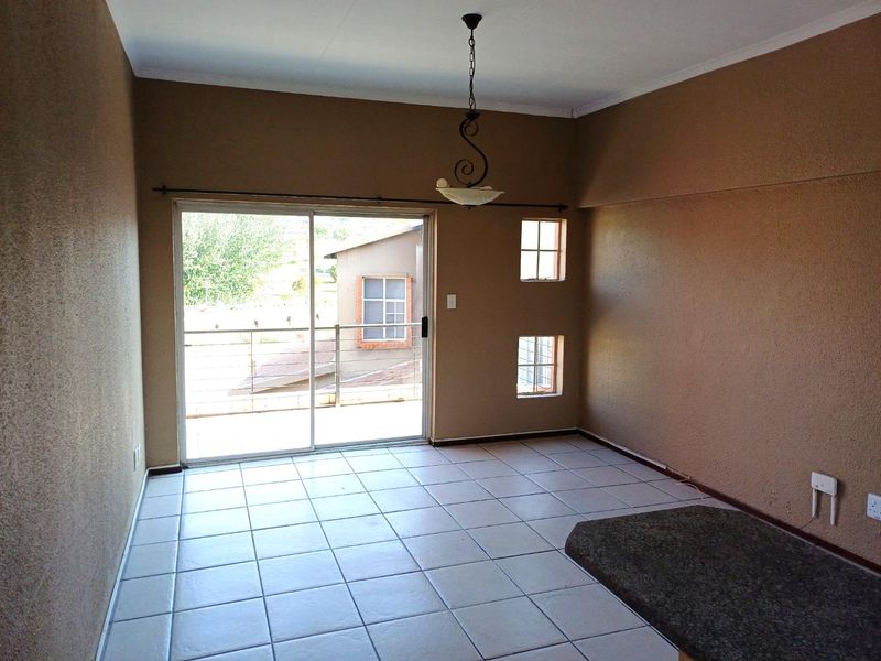An empty living area featuring tiled floors, a granite breakfast bar, and a sliding glass door leading to an outdoor balcony.