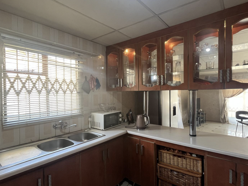A functional kitchen featuring wooden cabinetry, double bowl sink, and tiled splashbacks, offering a classic layout with potential for modern updates.