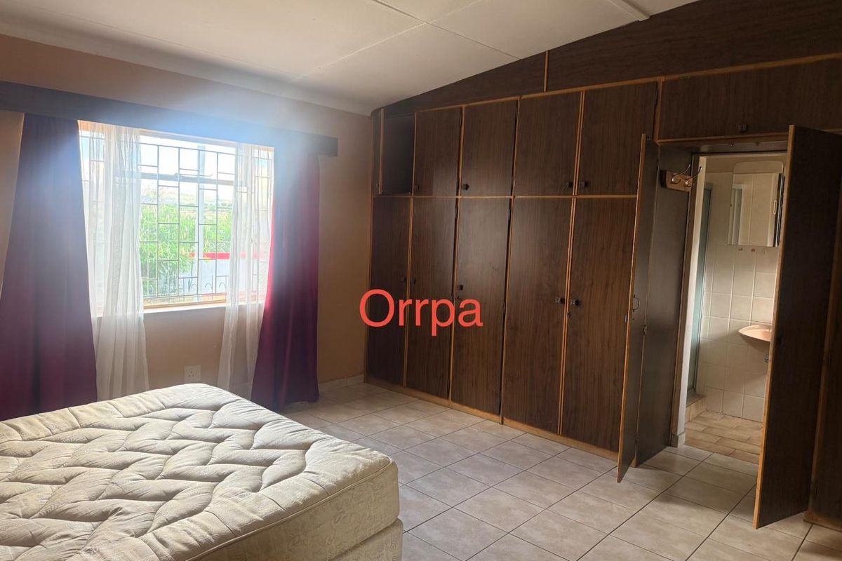 A bedroom featuring built-in wooden cabinetry, tiled flooring, and an en-suite bathroom access point.