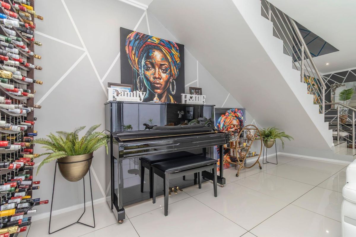 A modern living area featuring a staircase with stainless steel balustrades, tiled flooring, and a decorative wall finish under the stairs.