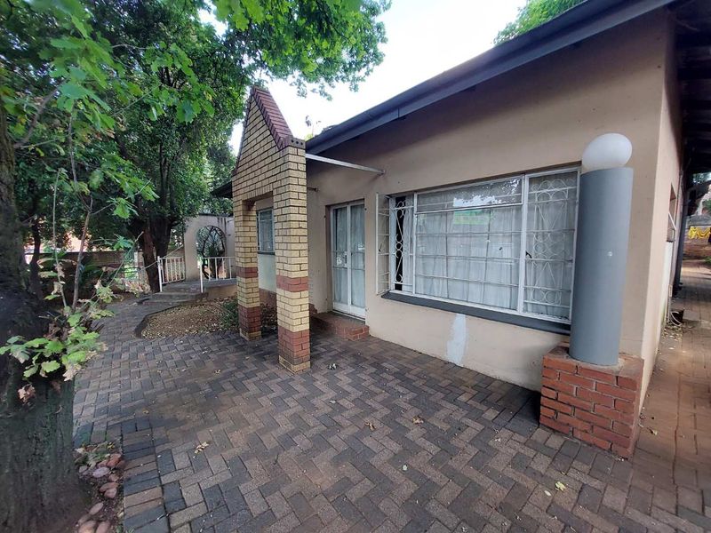 Rear exterior view of the apartment featuring a brick-paved patio area, security-fitted windows, and a covered entrance.