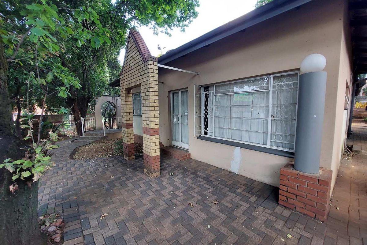 Rear exterior view of the apartment featuring a brick-paved patio area, security-fitted windows, and a covered entrance.