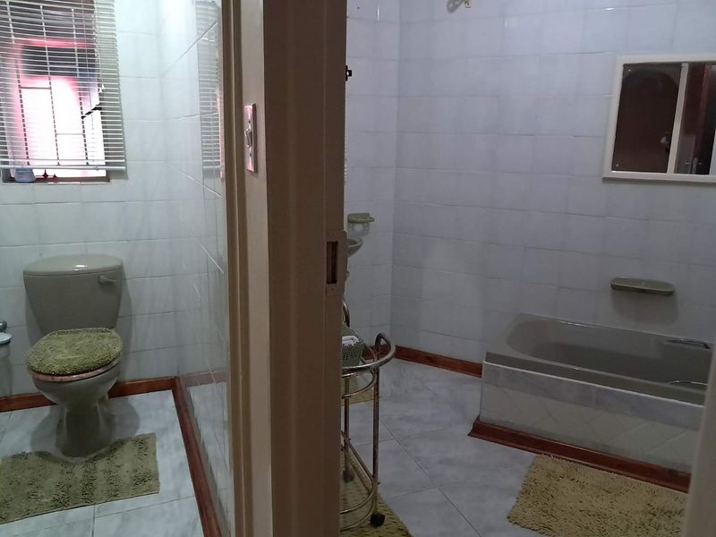 A functional bathroom featuring a bathtub, toilet, and fully tiled walls and floors, offering a clean and practical layout.