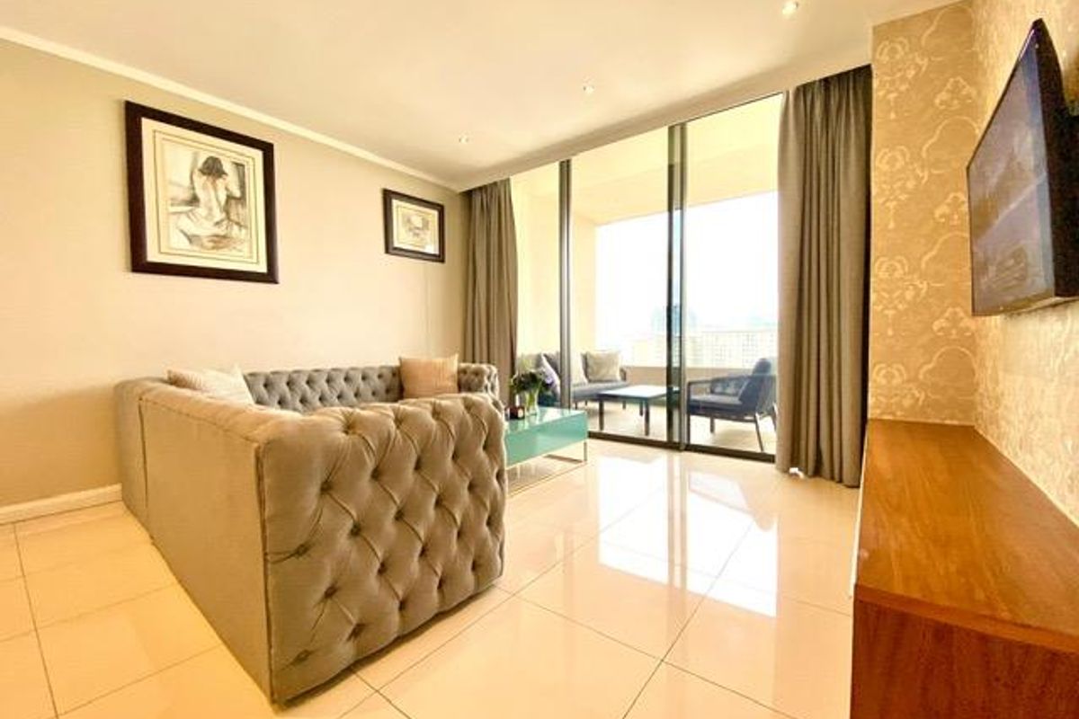 Modern living room featuring large sliding glass doors leading to a private balcony, polished tile flooring, and recessed ceiling lighting.