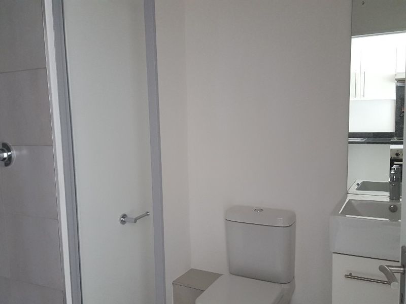 A clean, modern bathroom featuring a shower, toilet, and vanity with a basin and mirror.