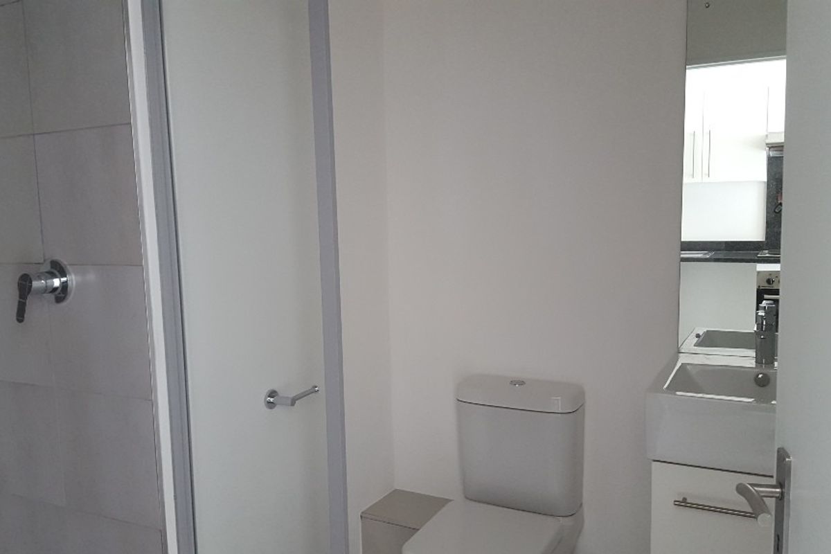 A clean, modern bathroom featuring a shower, toilet, and vanity with a basin and mirror.