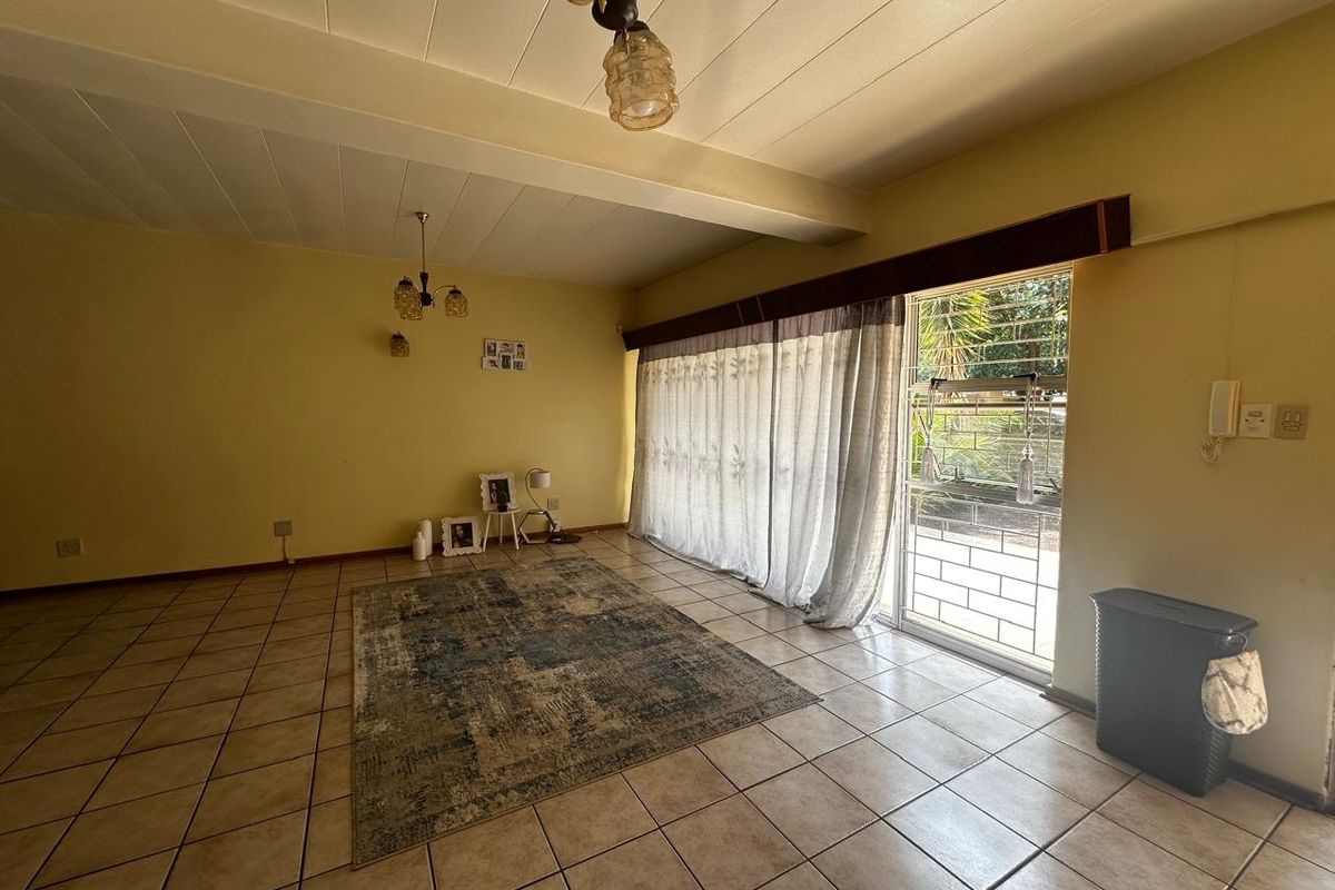 Spacious living room featuring tiled flooring, large sliding glass doors with security gate, and direct access to the outdoor area.