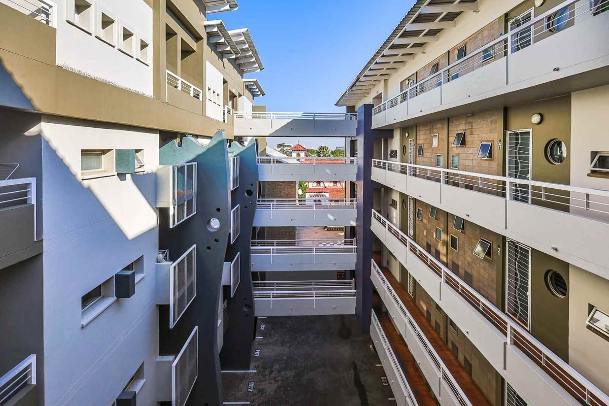 An elevated view of the apartment complex courtyard, featuring multi-level walkways, exterior building facades, and designated parking bays.
