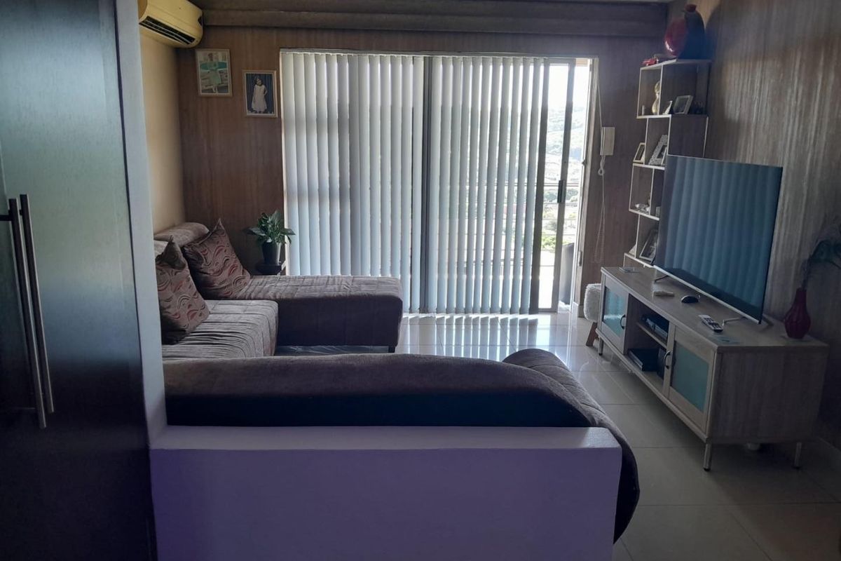 A living room featuring wood-look wall paneling, tiled flooring, and a sliding glass door leading to an outdoor area, equipped with a wall-mounted air conditioner.