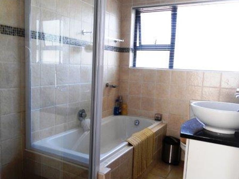 A functional bathroom featuring a separate shower enclosure, built-in bathtub, and a modern vessel sink set on a vanity cabinet with a granite countertop.