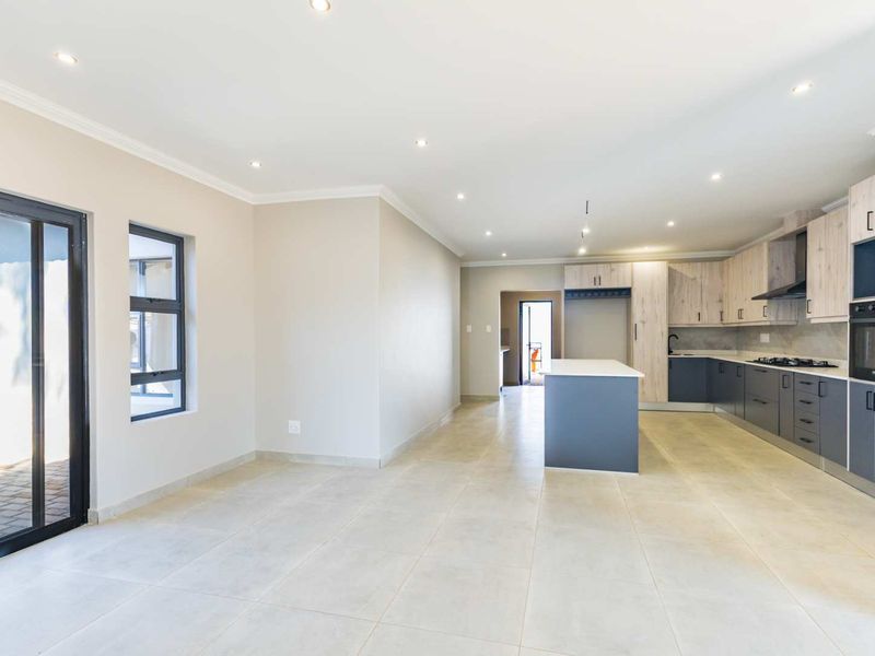 Spacious open-plan living and kitchen area featuring modern two-tone cabinetry, a central island, built-in appliances, and large sliding doors leading to the exterior.