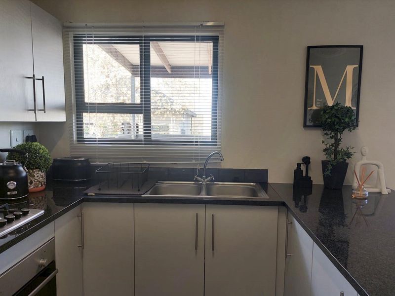 A well-maintained kitchen featuring modern cabinetry, granite countertops, a double basin sink, and integrated cooking appliances.