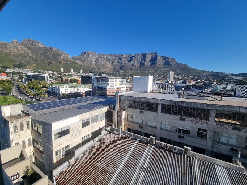 Elevated urban view overlooking surrounding industrial buildings with solar panel installations and a prominent mountain backdrop.