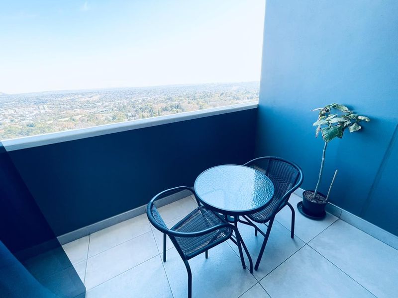 A private balcony featuring tiled flooring and a protective balustrade, offering expansive elevated views of the surrounding landscape.