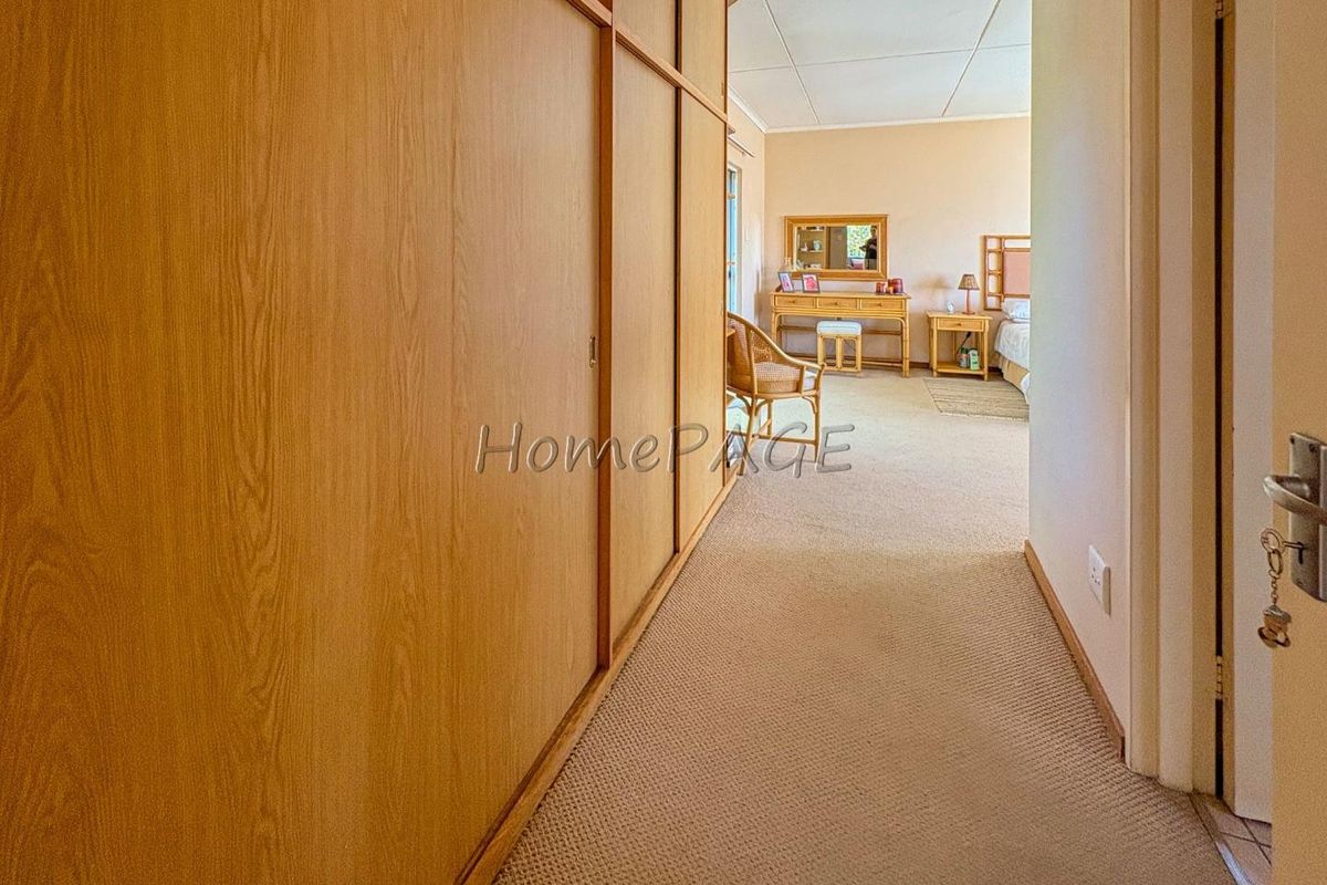 A bedroom featuring extensive built-in wooden cabinetry and neutral carpeting, leading into a spacious sleeping area.
