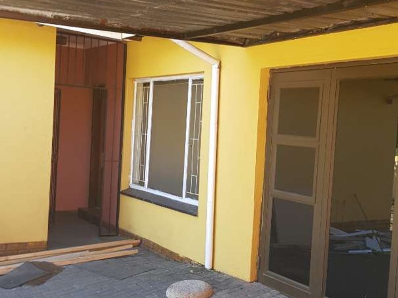 Covered outdoor patio area featuring paved flooring, aluminium window and door frames, and a corrugated metal roof structure.
