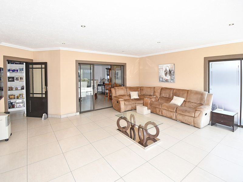 Spacious living room featuring neutral tiled flooring, recessed downlights, and sliding glass doors providing access to adjacent areas.