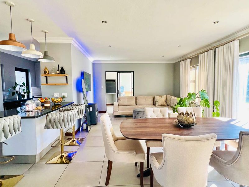 Spacious open-plan living area featuring a modern kitchen with island, dining space, and direct access to the patio through sliding glass doors.