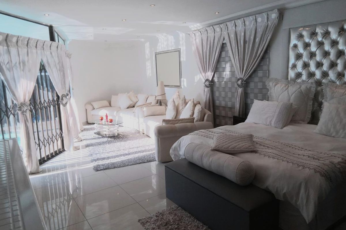 Spacious bedroom featuring tiled flooring, recessed ceiling lighting, and a large sliding door providing access to the outdoor area.