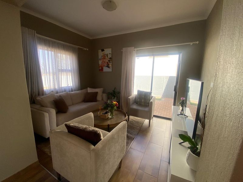 A cozy living room featuring tiled flooring and a sliding glass door providing direct access to the outdoor area.