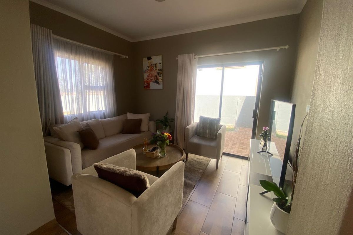 A cozy living room featuring tiled flooring and a sliding glass door providing direct access to the outdoor area.