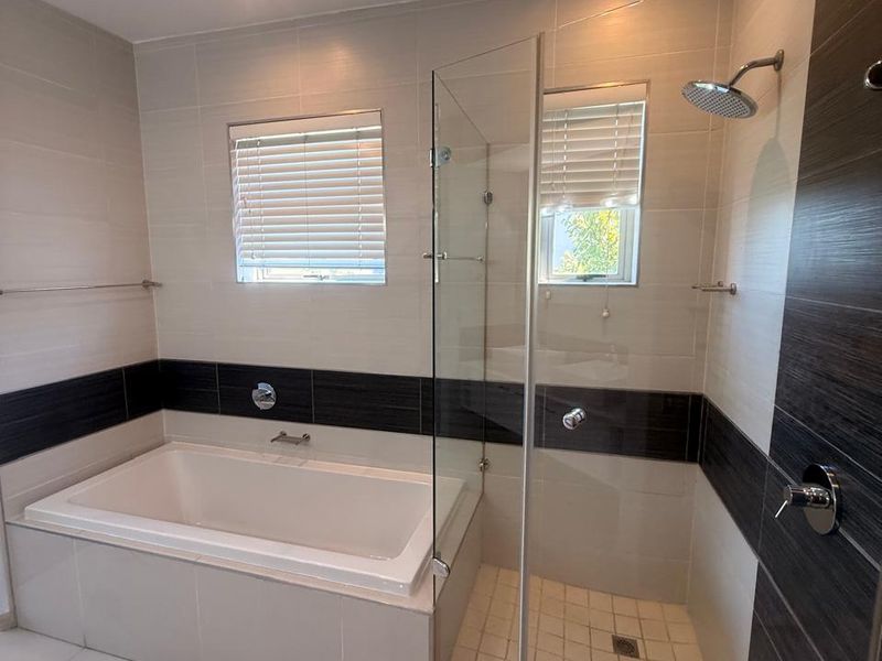 Modern bathroom featuring a built-in bathtub, a separate glass-enclosed shower, and contemporary wall and floor tiling.