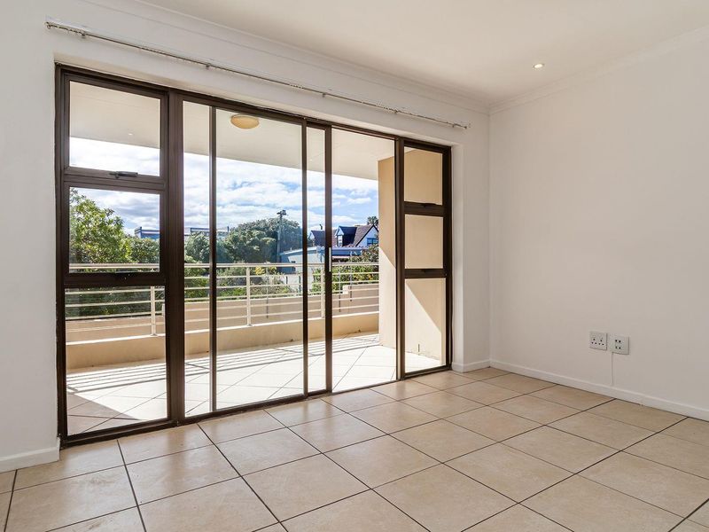 Bright and spacious living area featuring neutral tiled flooring and large sliding glass doors that open onto a private balcony.