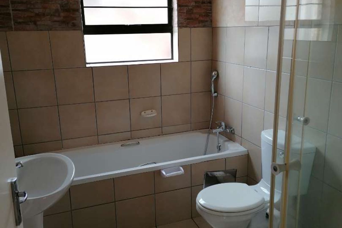 A functional bathroom featuring a bathtub, pedestal basin, toilet, and separate shower enclosure with tiled finishes throughout.
