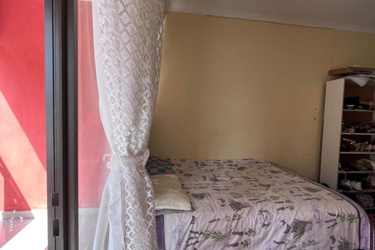 A bedroom featuring tiled flooring and a large sliding glass door providing direct access to an outdoor patio area.