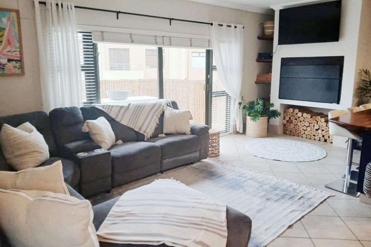 A comfortable living room featuring a built-in fireplace, tiled flooring, and large sliding glass doors that provide natural light and access to the exterior.