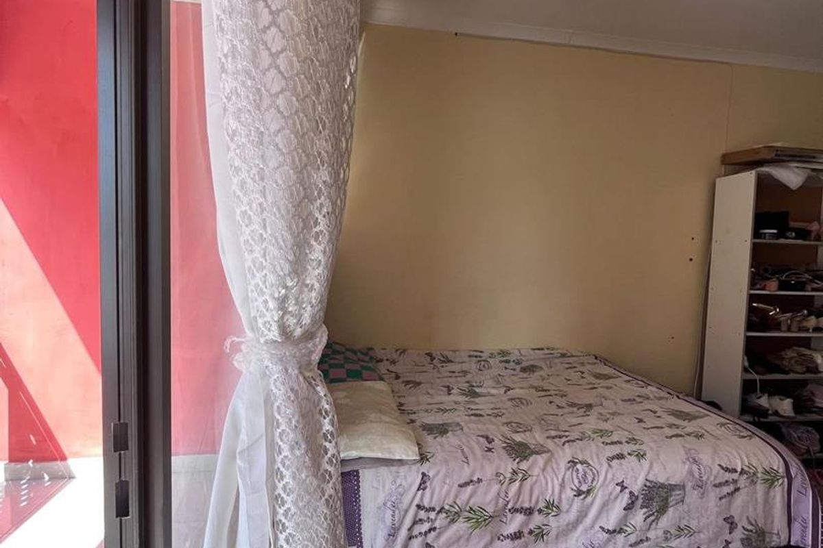 A bedroom featuring tiled flooring and sliding glass doors that provide direct access to an outdoor patio area.