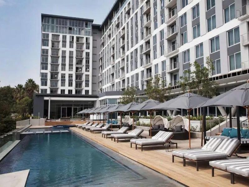 A modern apartment complex featuring a well-maintained swimming pool and spacious deck area with contemporary architectural design.