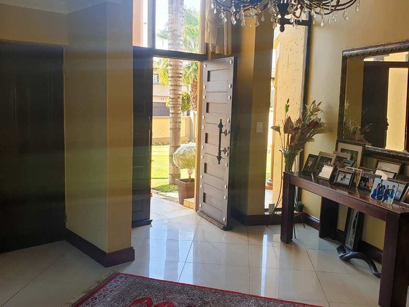Spacious entrance hall featuring polished tiled flooring, a decorative coffered ceiling, and an ornate chandelier, providing a welcoming transition into the home.