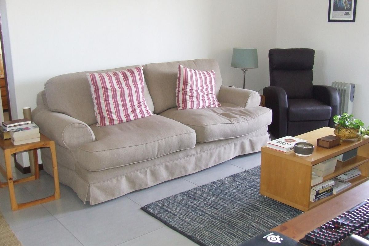 A living room featuring neutral tiled flooring and white walls, providing a clean and functional space for relaxation.