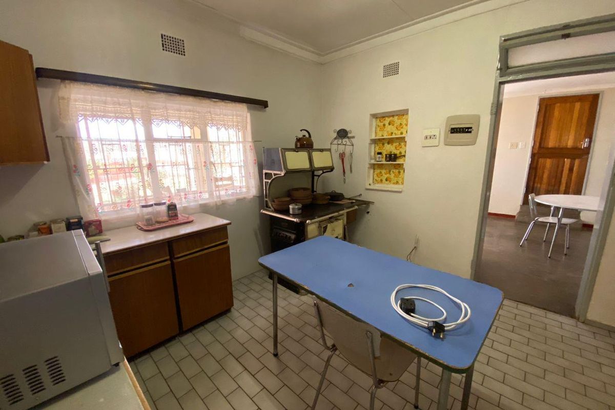A dated kitchen featuring original cabinetry, tiled flooring, and a vintage stove, offering a functional space with significant potential for modern renovation.